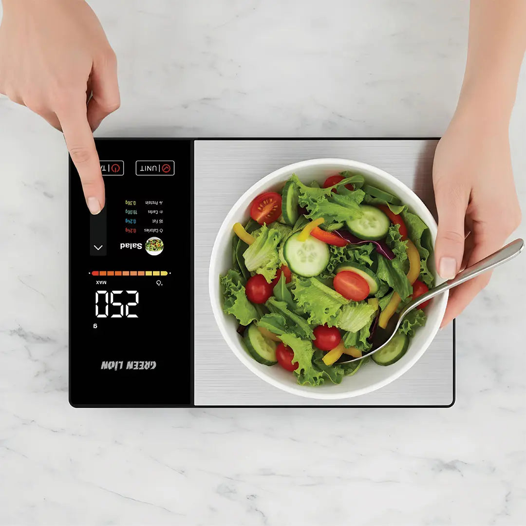Digital kitchen scale with a bowl of salad on a marble surface